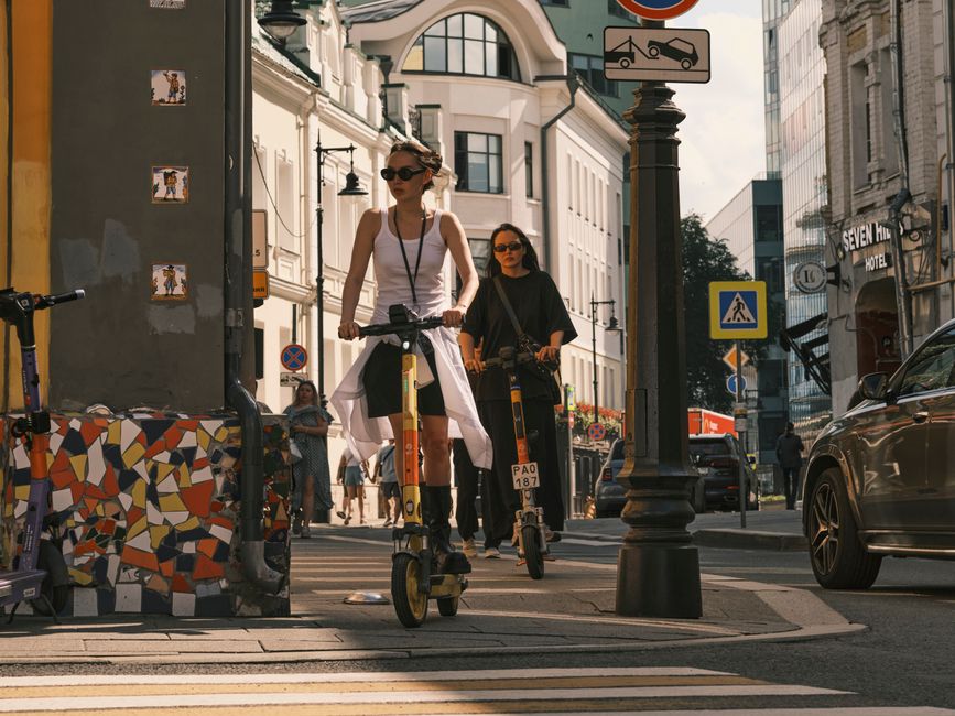 Een elektrische step met kenteken op straat, gebruikt door een jongere in een stedelijke omgeving.